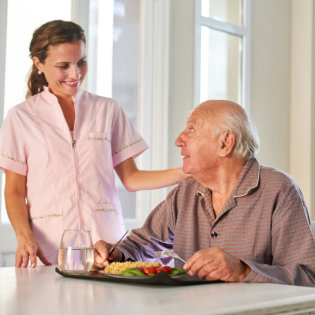 Female caregiver giving assistance to an elderly man