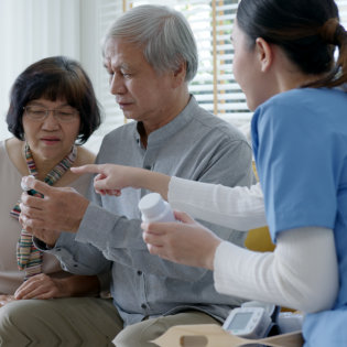 caregiver explain medication to senior couple