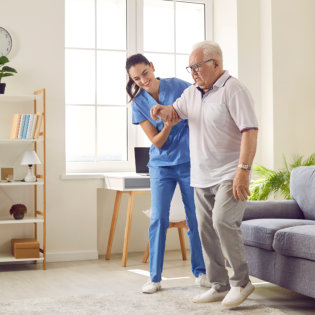 Smiling caregiver helping senior man to stand up