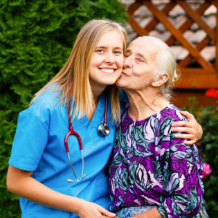 senior woman kissing female nurse in the cheek