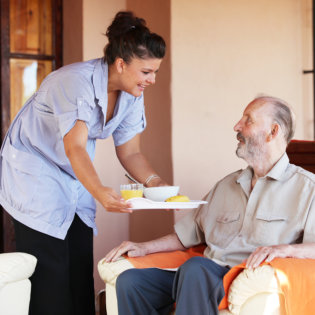 caregiver serving food to senior man