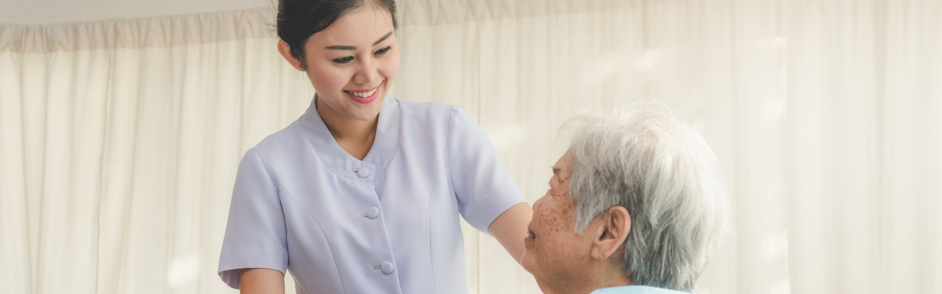 female caregiver and an elderly woman looking at each other